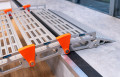 Close up of rest on connection on a step of a portable rollable aluminium wheelchair ramp resting on a step