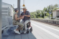 Rollator with seat in use as train station 