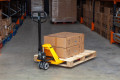 Pallet truck being used to move a wooden pallet in the warehouse 