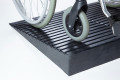 Manual wheelchair going up rubber threshold ramp 