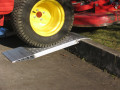 Pair of aluminium container ramps resting on kerb with vehicle driving up 