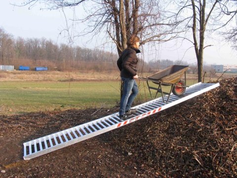 Person walking up skip ramp with wheelbarrow 