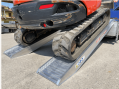 Rubber tracked digger driving up ramps 