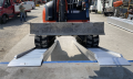 pair of loading ramps with digger driving on them 