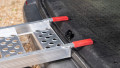 Single aluminium lightweight motorcycle ramp resting on the boot of a vehicle, close up of the red finger style rest on connection