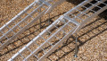 pair of motorbike ramps with support legs resting on the back of a vehicle, close up of ramp surface and support legs