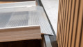 Close up of the rest on connection of a wheelchair ramp without handrails resting on a step. Shows the pre-drilled holes where the ramp can be fixed in place.