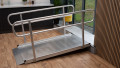 An empty wheelchair ramp with handrails resting on a step