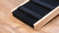 Bottom end of a wooden pet step showing the carpet surface