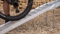 Single motorbike ramp with support legs resting on a vehicle with a push bike being loaded - close up view of the bar grip surface