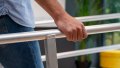 A close up of the handrails of our wheelchair ramps with handrails. A pedestrian is walking up and holding onto the handrails