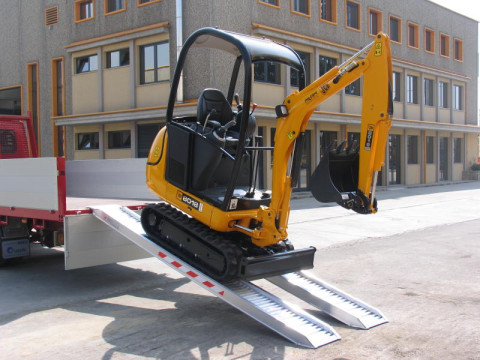 Mini digger driving down aluminium ramps 