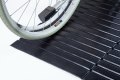 Manual wheelchair going up rubber wedge threshold ramp 