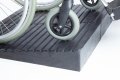 Manual wheelchair going up rubber threshold ramp 