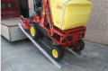 machine driving up ramps onto flat bed van 