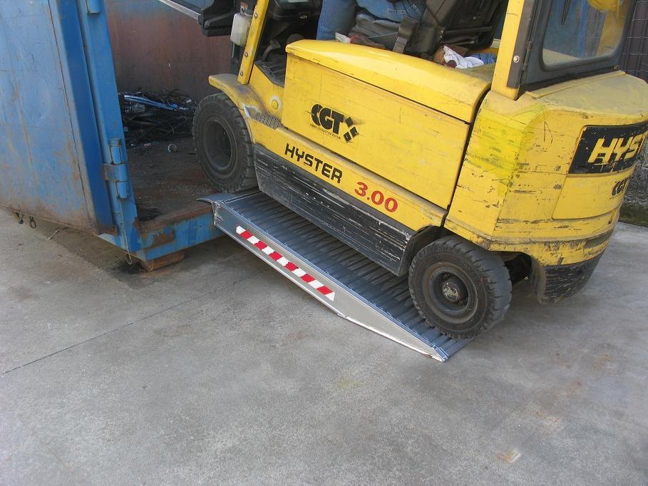 Forklift driving up aluminium ramps into a container Forklift driving up aluminium ramps into a container