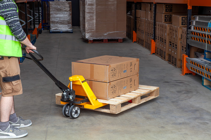 Warehouse worker using manual pallet truck to move a pallet 