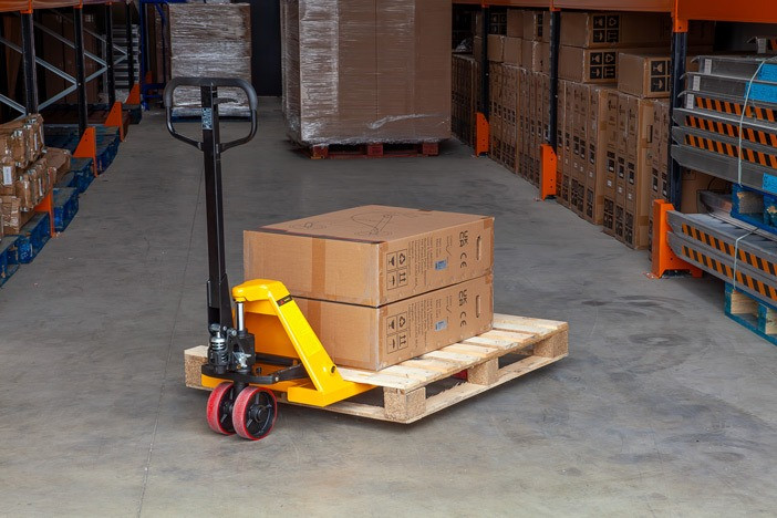 Manual Pallet Truck in warehouse being used to move a pallet with two boxes 