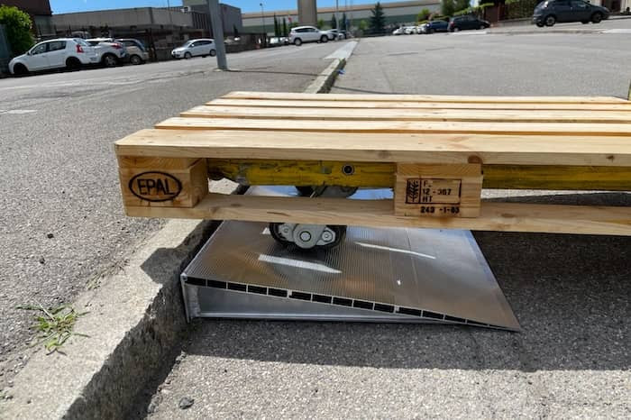 Manual pallet truck going up a ramp to overcome a kerb 