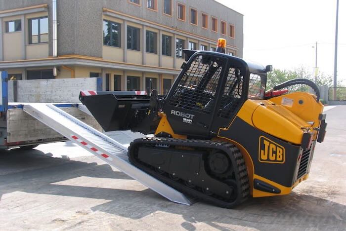JCB rubber tracked machine driving up pair of aluminium loading ramps JCB rubber tracked machine driving up pair of aluminium loading ramps